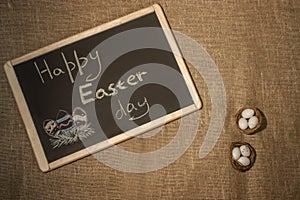 Happy Easter chalk board. Nest with eggs on a sackcloth. Happy Easter eggs. Background with easter eggs.