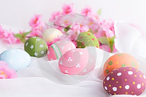 Happy easter! Colorful of Easter eggs in nest with flower and Feather on white cheesecloth background