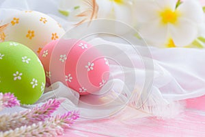 Happy easter! Colorful of Easter eggs in nest with flower, paper star and Feather on white cheesecloth and bright pink pastel