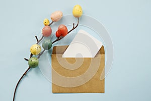 Happy Easter composition with Easter colored eggs and paper blank on a pastel blue background. Flat lay, top view, copy space