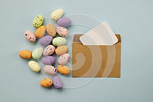 Happy Easter composition with Easter colored eggs and paper blank on a pastel blue background. Flat lay, top view, copy space