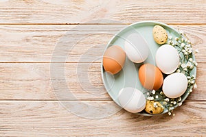 Happy Easter composition. Easter eggs in basket on colored table with gypsophila. Natural dyed colorful eggs background