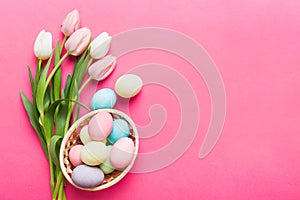 Happy Easter composition. Easter eggs in basket on colored table with yellow Tulips. Natural dyed colorful eggs