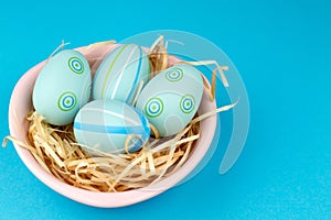 Happy easter composition. Nest with blue pained easter eggs. Texture blue background. Flat lay, top view and copyspace