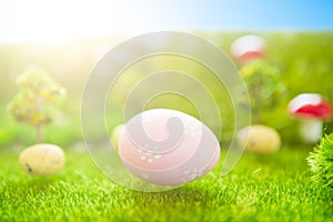 Happy Easter concept. Colorful easter eggs and one big pink easter egg on spring green grass. Fairy tale sunset on the