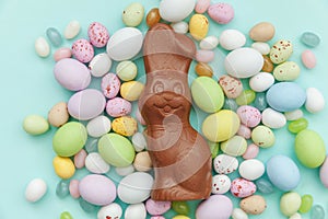 Happy Easter concept. Easter candy chocolate eggs bunny and jellybean sweets isolated on trendy pastel blue background. Simple