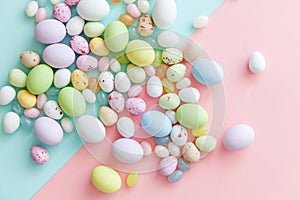 Happy Easter concept. Easter candy chocolate eggs and jellybean sweets isolated on trendy pastel blue pink background. Simple