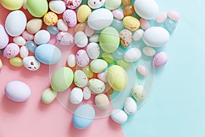 Happy Easter concept. Easter candy chocolate eggs and jellybean sweets isolated on trendy pastel blue pink background. Simple