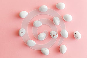 Happy Easter concept. Easter candy chocolate eggs and jellybean sweets isolated on trendy pastel pink background. Simple