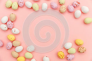 Happy Easter concept. Easter candy chocolate eggs and jellybean sweets isolated on trendy pastel pink background. Simple