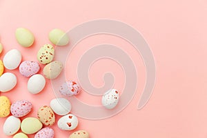 Happy Easter concept. Easter candy chocolate eggs and jellybean sweets isolated on trendy pastel pink background. Simple