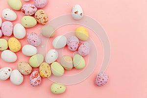 Happy Easter concept. Easter candy chocolate eggs and jellybean sweets isolated on trendy pastel pink background. Simple