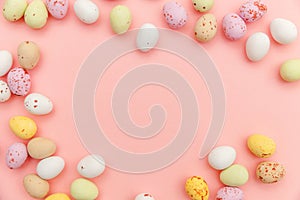 Happy Easter concept. Easter candy chocolate eggs and jellybean sweets isolated on trendy pastel pink background. Simple
