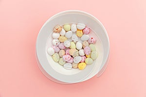 Happy Easter concept. Easter candy chocolate eggs and jellybean sweets isolated on trendy pastel pink background. Simple