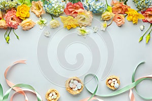 Happy Easter concept with easter eggs in nest and spring flowers. Easter background with copy space. Flat lay