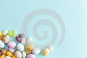 Happy Easter concept. Preparation for holiday. Easter candy chocolate eggs and jellybean sweets isolated on trendy pastel blue