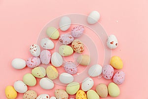 Happy Easter concept. Preparation for holiday. Easter candy chocolate eggs and jellybean sweets isolated on trendy pastel pink