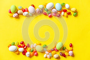 Happy Easter concept. Preparation for holiday. Easter candy chocolate eggs and jellybean sweets isolated on trendy yellow