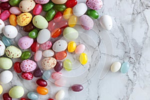 Happy Easter concept. Preparation for holiday. Easter candy chocolate eggs and jellybean sweets on trendy gray marble background.