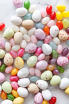 Happy Easter concept. Preparation for holiday. Easter candy chocolate eggs and jellybean sweets on trendy gray marble background.