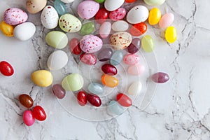 Happy Easter concept. Preparation for holiday. Easter candy chocolate eggs and jellybean sweets on trendy gray marble background.