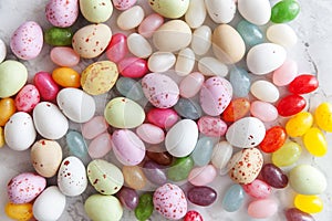 Happy Easter concept. Preparation for holiday. Easter candy chocolate eggs and jellybean sweets on trendy gray marble background.