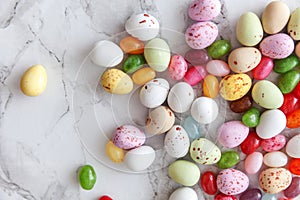 Happy Easter concept. Preparation for holiday. Easter candy chocolate eggs and jellybean sweets on trendy gray marble background.