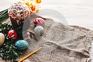 happy Easter concept. stylish painted eggs and easter cake on white rustic wooden background with spring flowers and candle. seas