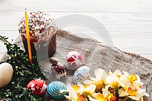 happy Easter concept. stylish painted eggs and easter cake on white rustic wooden background with spring flowers and candle. seas