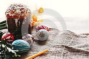 happy Easter concept. stylish painted eggs and easter cake on white rustic wooden background with spring flowers and candle. seas