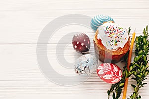 happy Easter concept. stylish painted eggs and easter cake on white rustic wooden background with spring flowers and candle. seas