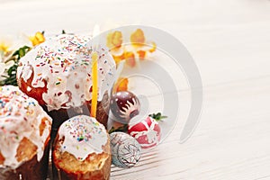 happy Easter concept. stylish painted eggs and easter cake on white rustic wooden background with spring flowers and candle. seas