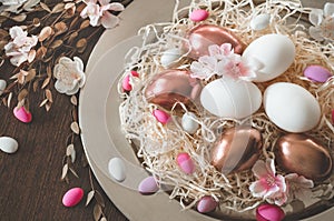 Happy Easter. Congratulatory easter background. Easter eggs on a metal plate with spring flowers on a wooden background