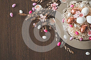 Happy Easter. Congratulatory easter background. Easter eggs on a metal plate with spring flowers on a wooden background