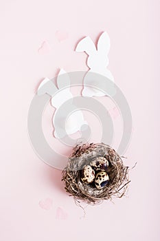 Happy easter couple of white rabbits and quail eggs in nest on pink background top and verical view