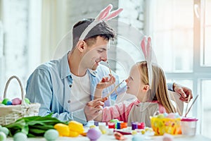 Happy easter!Dad and his little daughter together have fun while preparing for Easter holidays.On the table is a basket with