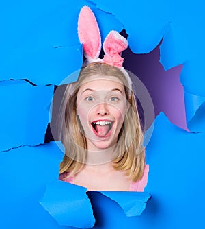 Happy Easter day. Smiling girl in bunny ears looking through paper hole. Happy woman in rabbit ears. Easter bunny