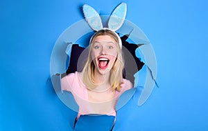 Happy Easter Day. Smiling Woman in bunny ears looking through paper hole. Rabbit girl on holiday.