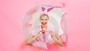 Happy Easter day. Smiling woman in bunny ears painting eggs for Easter holiday. Rabbir gitl with painted Easter egg. Egg