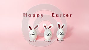 Happy Easter Day. Three cute bunnies made of white chicken eggs isolated on a light pink pastel background