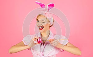 Happy easter day. Winking woman in rabbit ears decorating eggs. Smiling bunny girl Painting egg.