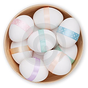 Happy Easter decorations, basket full of easter eggs with ribbon in pastel light colors, top view on white background. Template