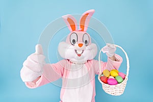 Happy easter. Easter bunny or rabbit or hare holds egg with basket of colored eggs, having fun, celebrates Easter rabbit