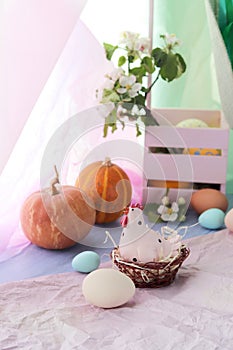 Happy Easter, eggs, toy chicken, pumpkins, apple tree flowers in a basket on a windowsill