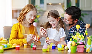 Happy easter! family mother, father and child daughter paint eggs for holiday