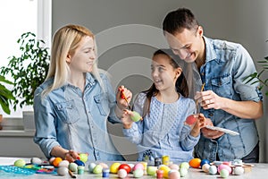 Happy easter! family mother, father and children having fun paint and decorate eggs for holiday