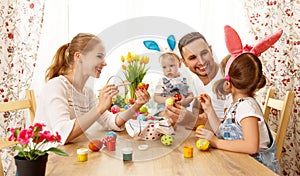 Happy easter! family mother, father and children paint eggs for