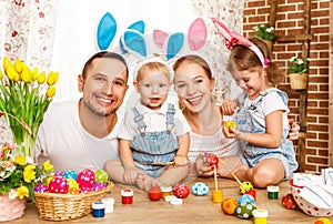 Happy easter! family mother, father and children paint eggs for