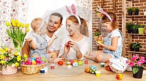 Happy easter! family mother, father and children paint eggs for