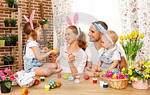 Happy easter! family mother, father and children paint eggs for